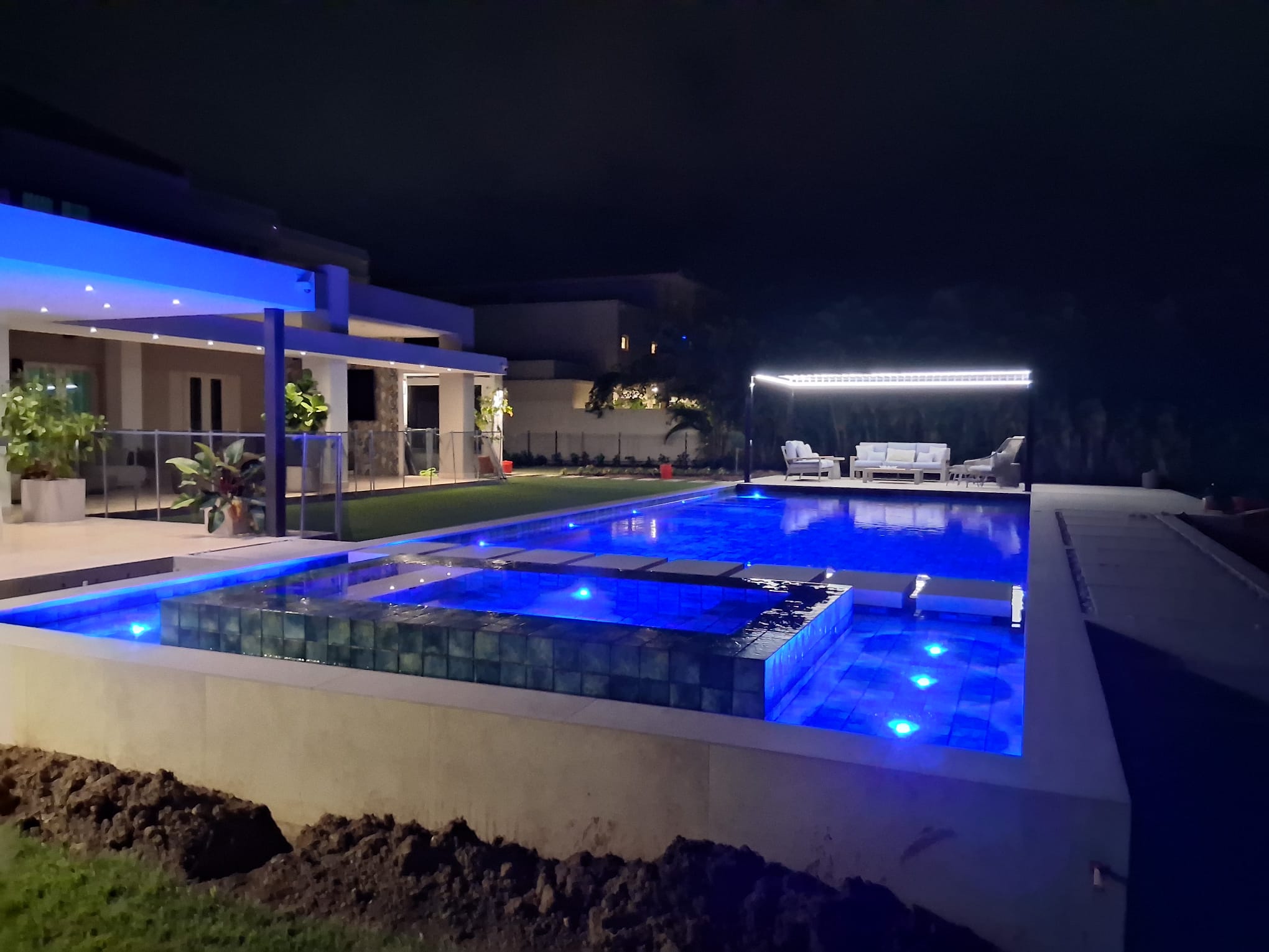 Piscina iluminada de noche junto a una residencia moderna